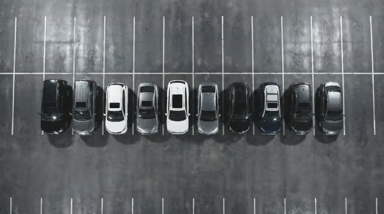 Ten Rochester Car Rental vehicles photographed from directly overhead, parked in a single line across marked bays.